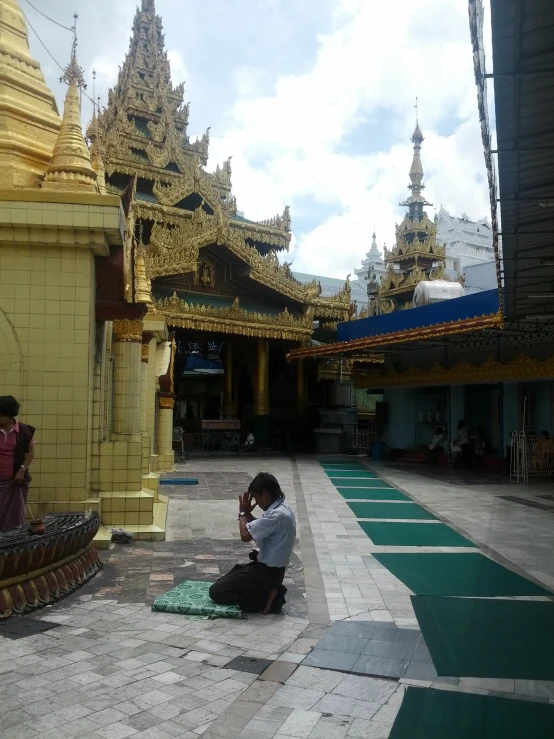 a man sits on the floor with his camera up to his ear