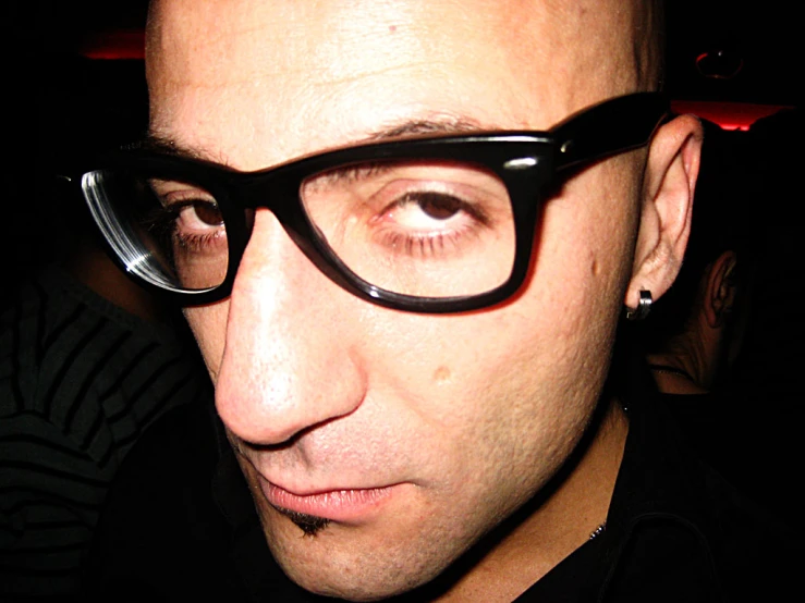 a man in black glasses staring into the camera