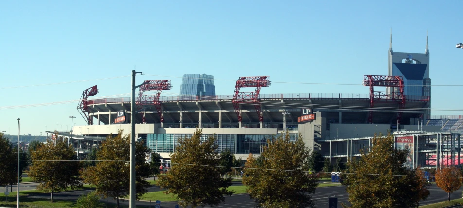 a baseball stadium with trees and fence surrounding it