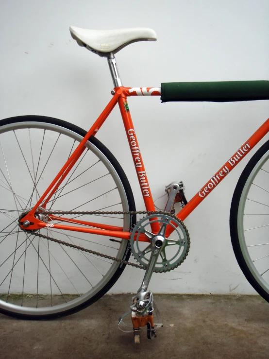 a orange bicycle is sitting against a wall