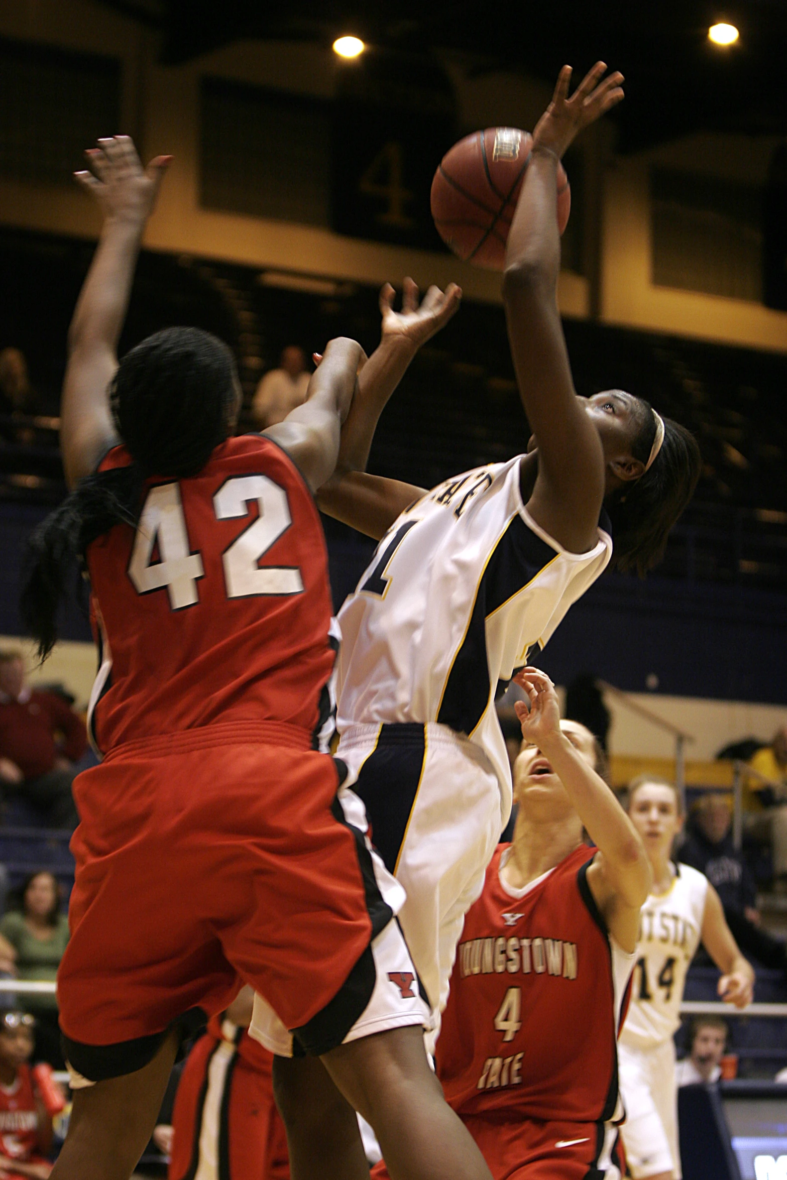 two girls are playing basketball with the crowd watching