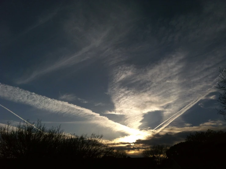 a very cloudy sky above some trees at sunset