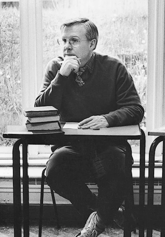 a black and white po of a man with books sitting on a table