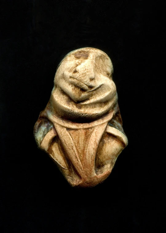 a carved stone object on display in a black room
