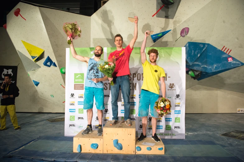 three boys standing on top of a small statue holding up flowers