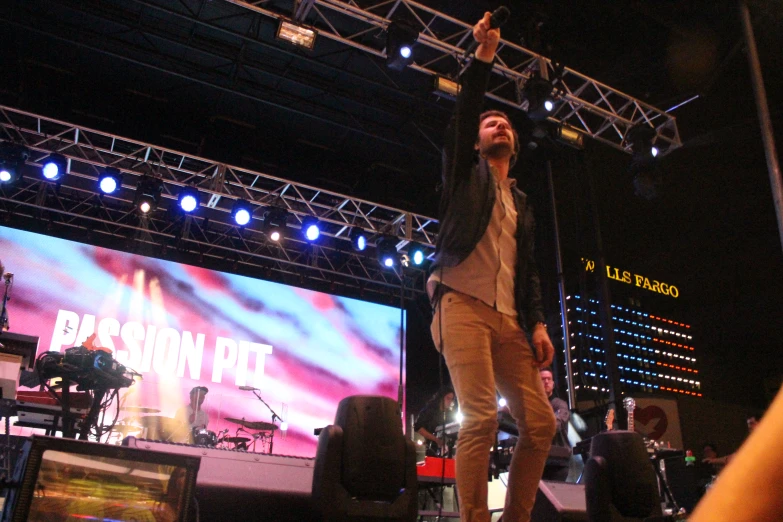 a guy is singing on stage in front of two large screens