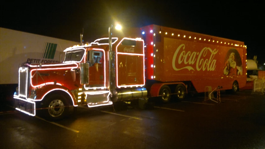 an advertit truck parked in a parking lot covered with lights
