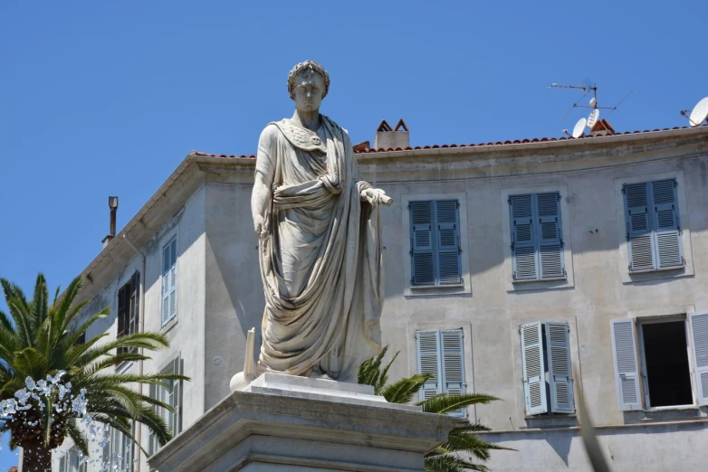 the statue in front of the house has palm trees in front of it