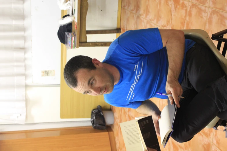 a man sitting in a chair with his book on the back of his lap