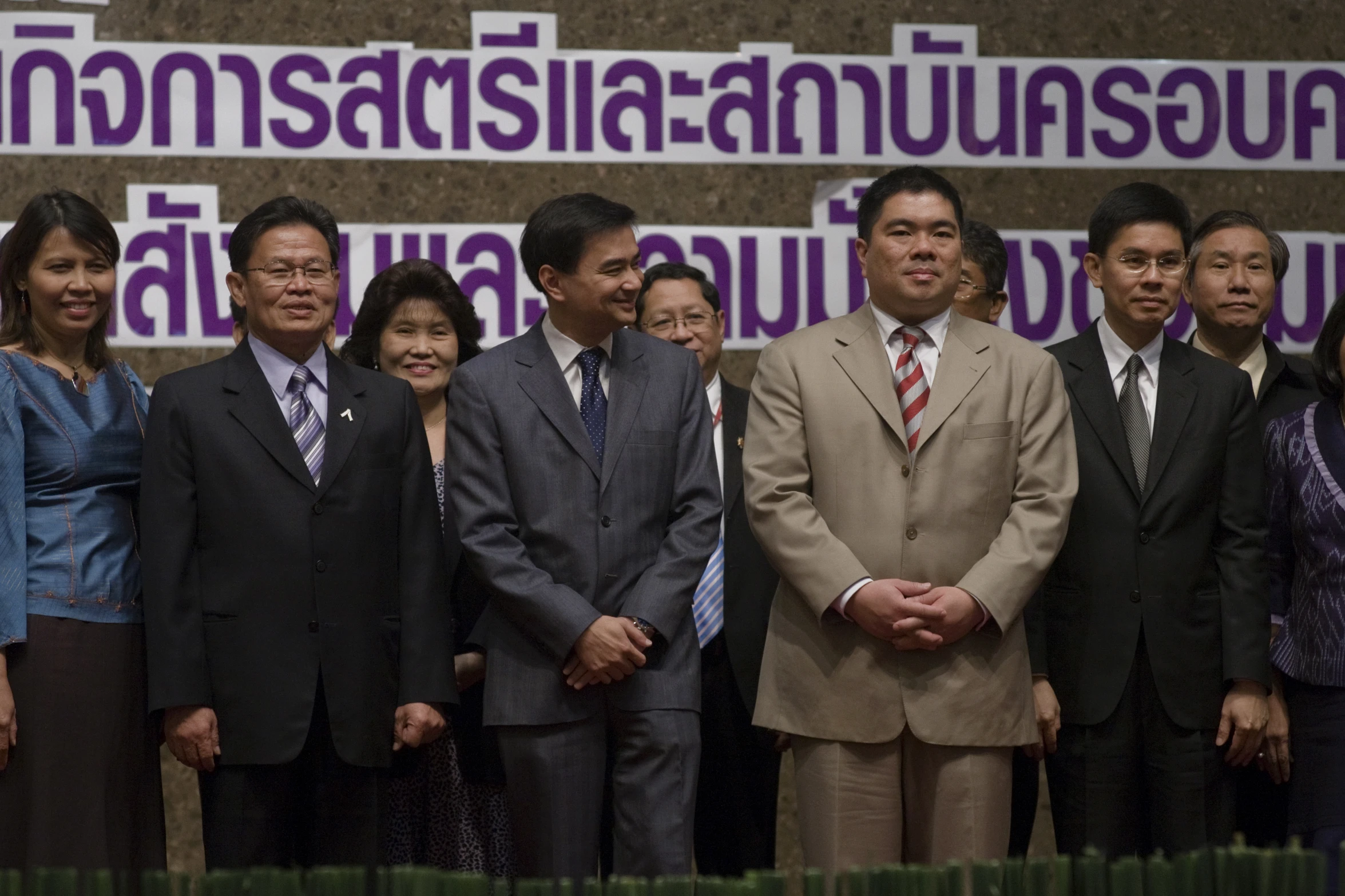 several business people standing in front of a purple banner