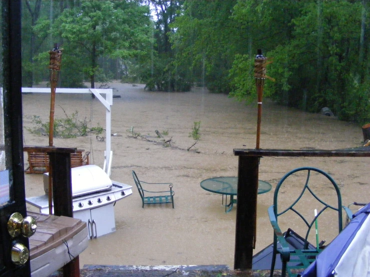 a view of the outside of a patio with table, chairs and grill