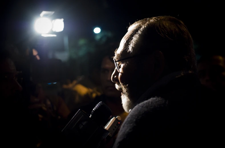 man talking in a dark room with lights on