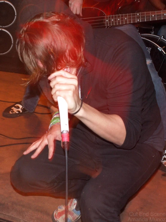 a man is kneeling down while playing guitar