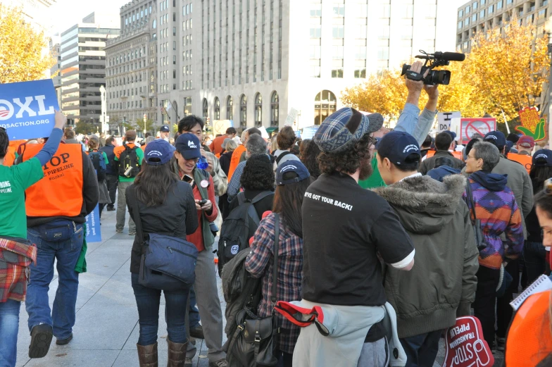 a crowd is protesting on the sidewalk by buildings