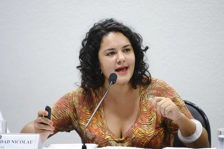 a women with curly hair and a microphone is making a point