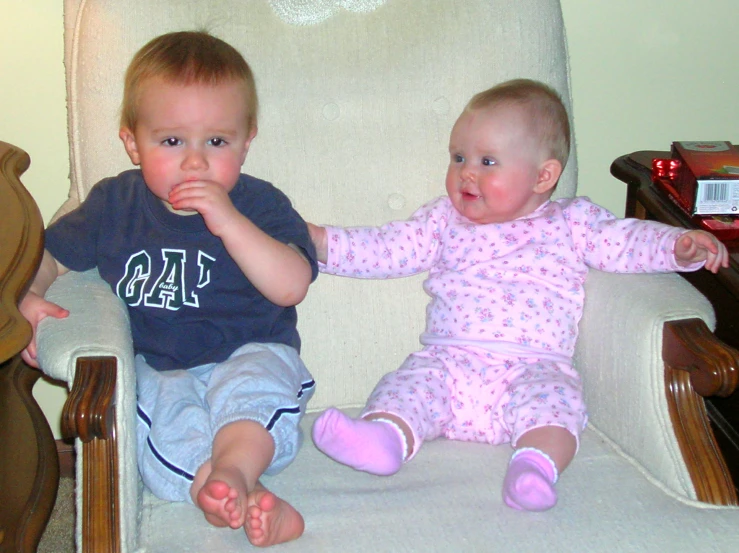 two small children sit in chairs next to each other