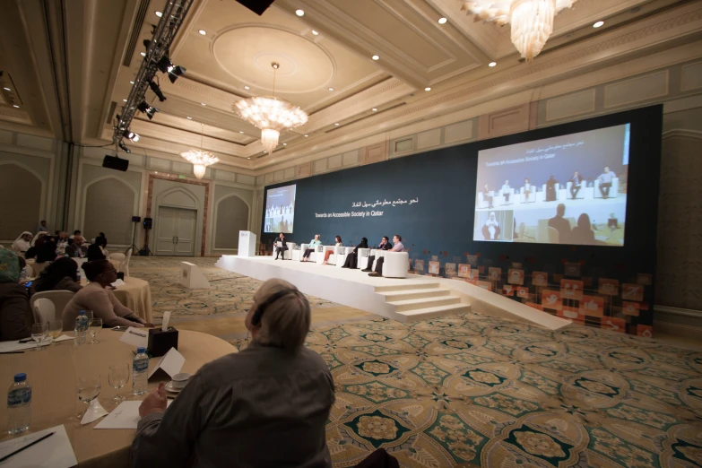 a large room filled with people and two women on stage speaking