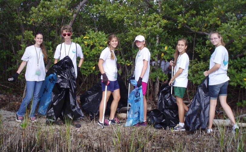 seven young people with a trash bag in front of them