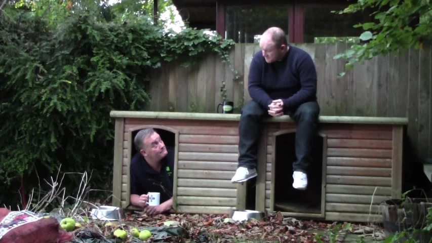 a man sitting on the roof of a wood shed looking into another man's eyes