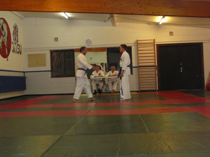 men in karate kims practicing with each other in the gym