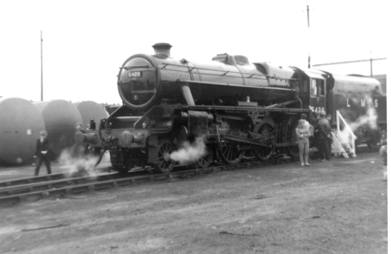 some people are standing next to a steam train