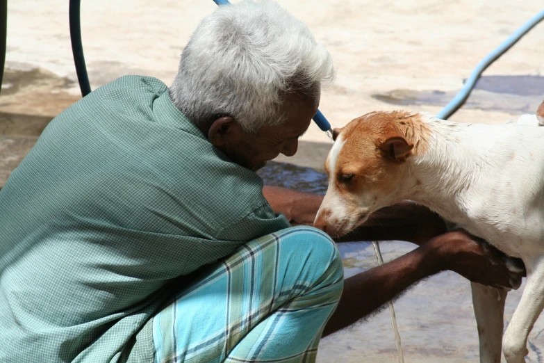 a old man in plaid pants is kissing his dog