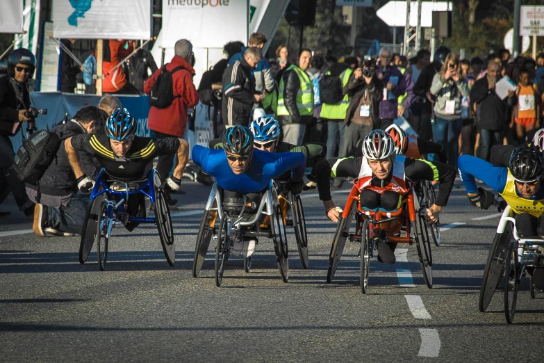 bicyclists ride down the street while spectators watch