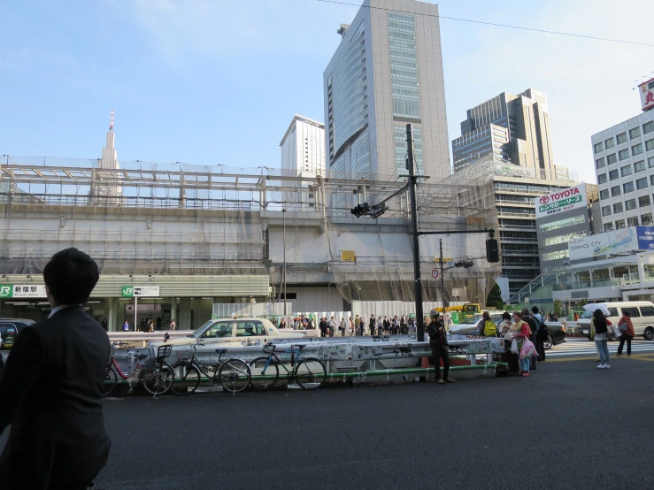 people walking and sitting on benches near a busy street