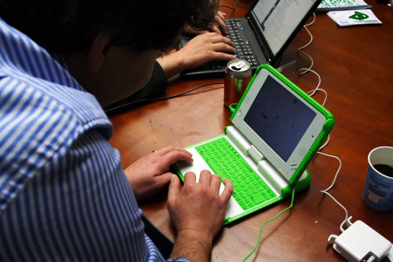man sitting at a desk with a laptop computer and a green netbook