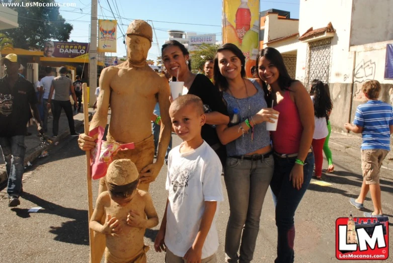a man in a statue made of sand poses for the camera with two women and a little boy