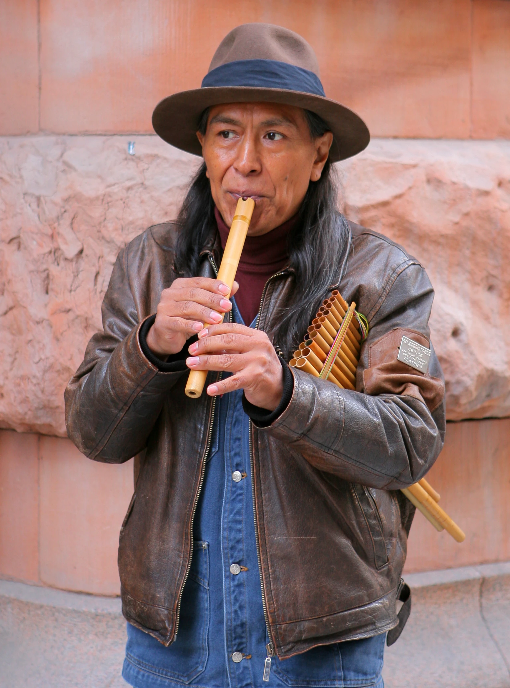 an asian man playing a pipe flute on the street