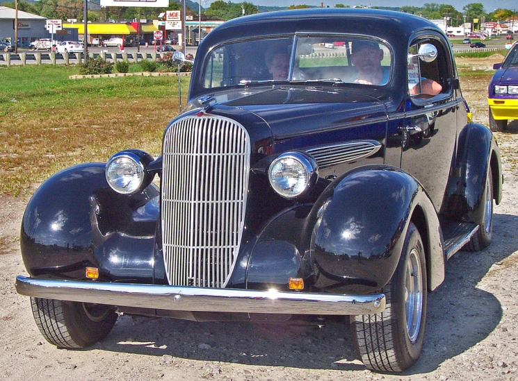 a classic car is parked on the dirt