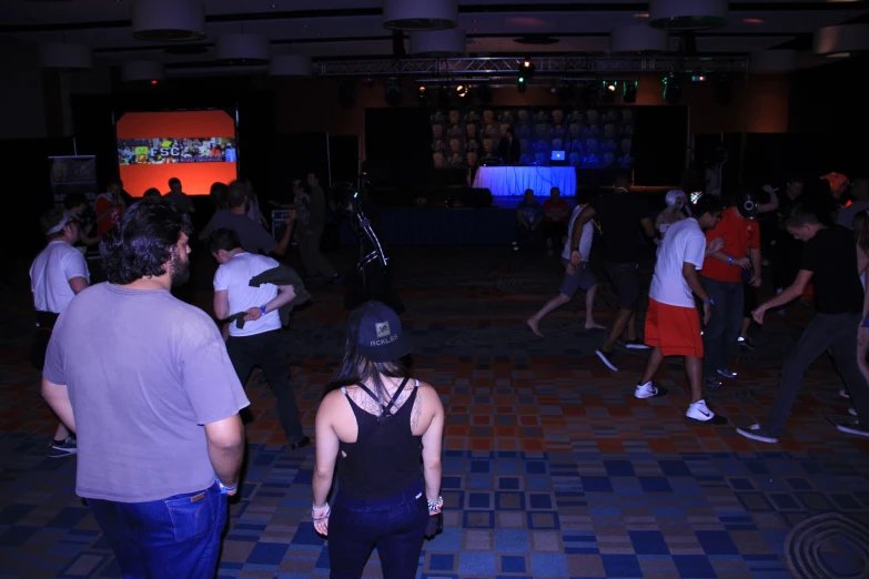 a large group of people are dancing in a room