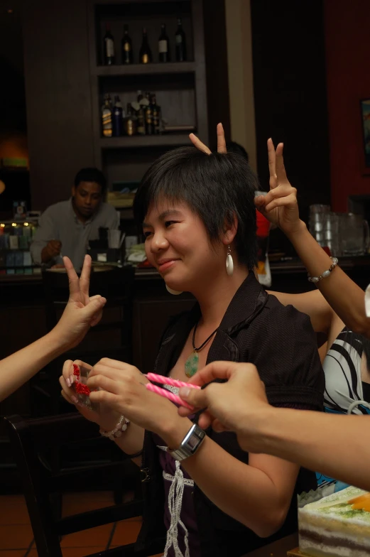 three women at a restaurant doing the number two gesture
