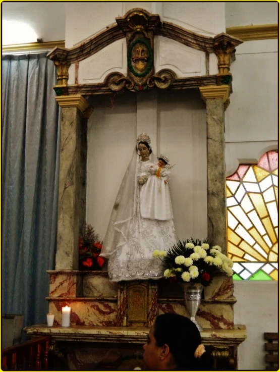 a small altar with a large statue of a woman dressed in white