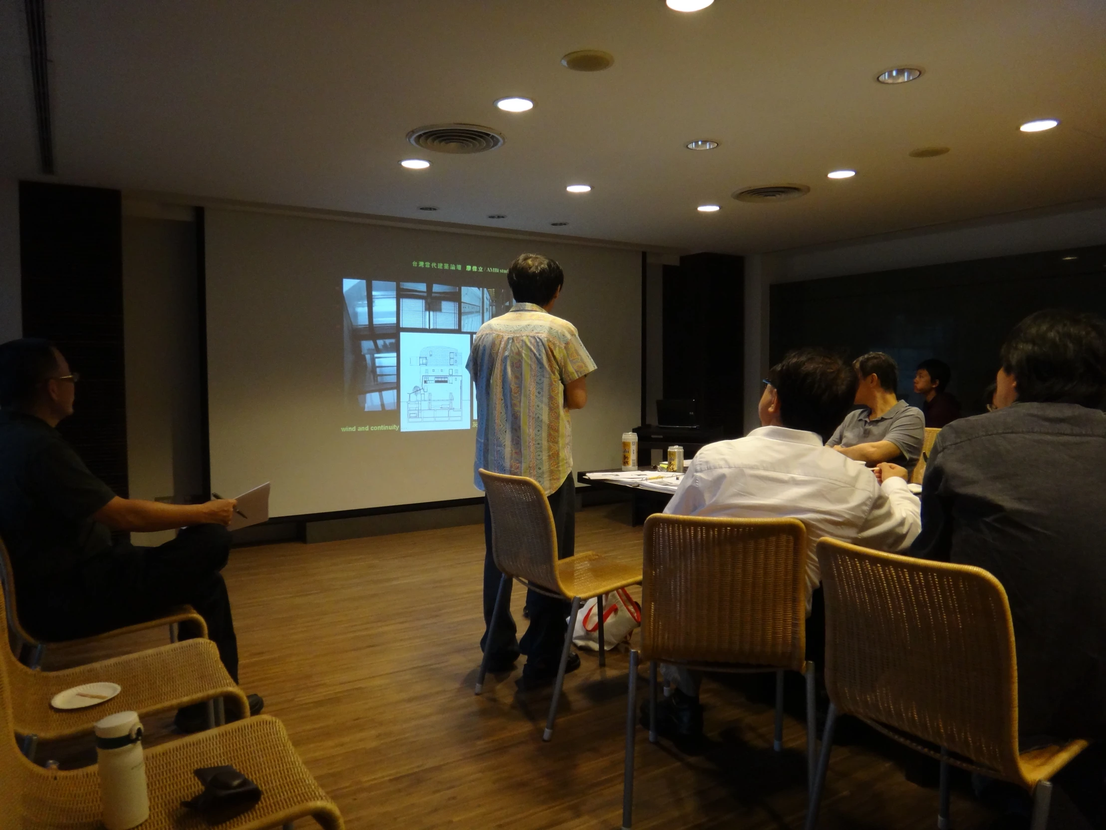 group of people sitting in chairs with a man on the screen