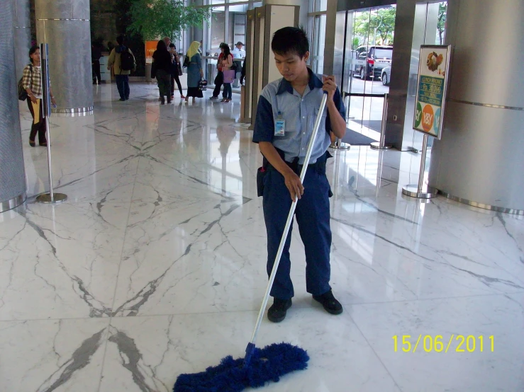 a man with a mop stands in the lobby while cleaning