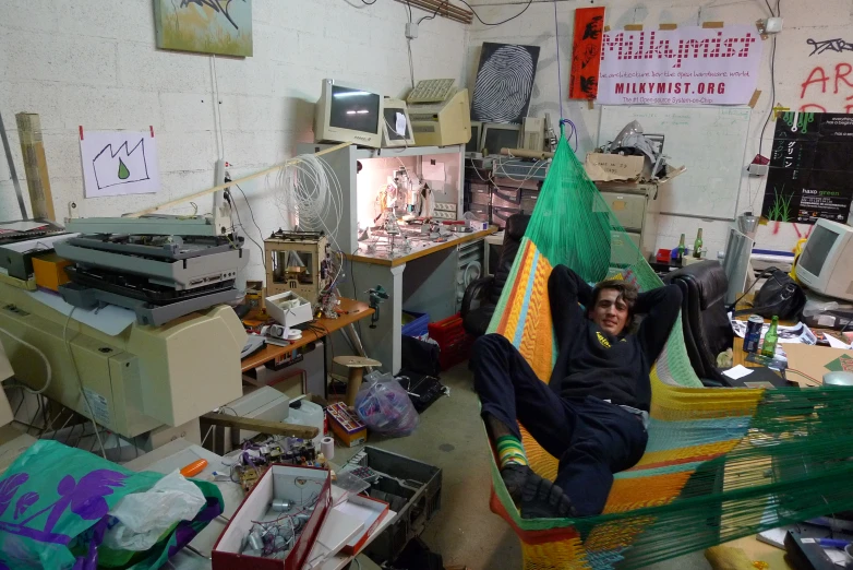 a man sitting in a hammock inside of a room