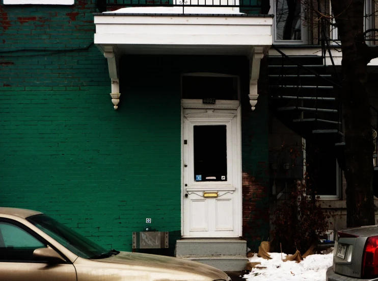 cars parked in front of green brick building