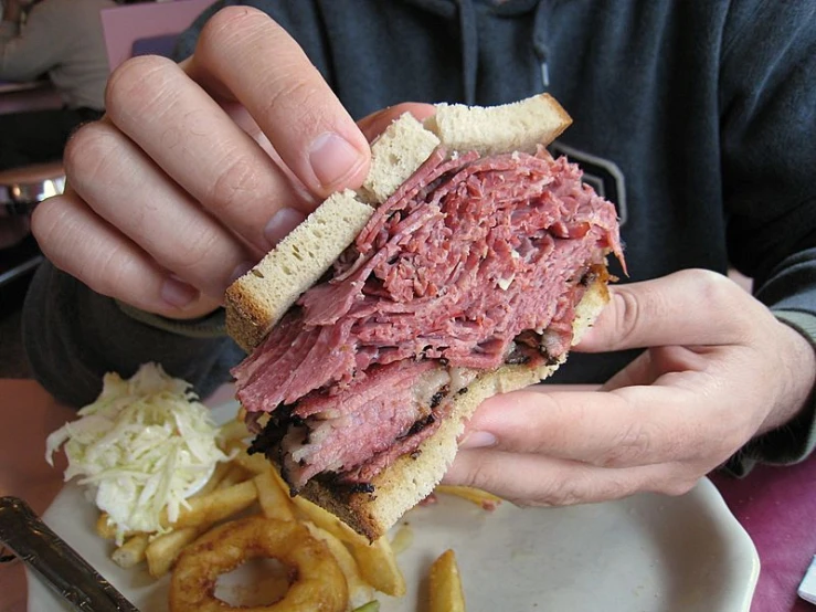 a man is holding up a sandwich while eating french fries