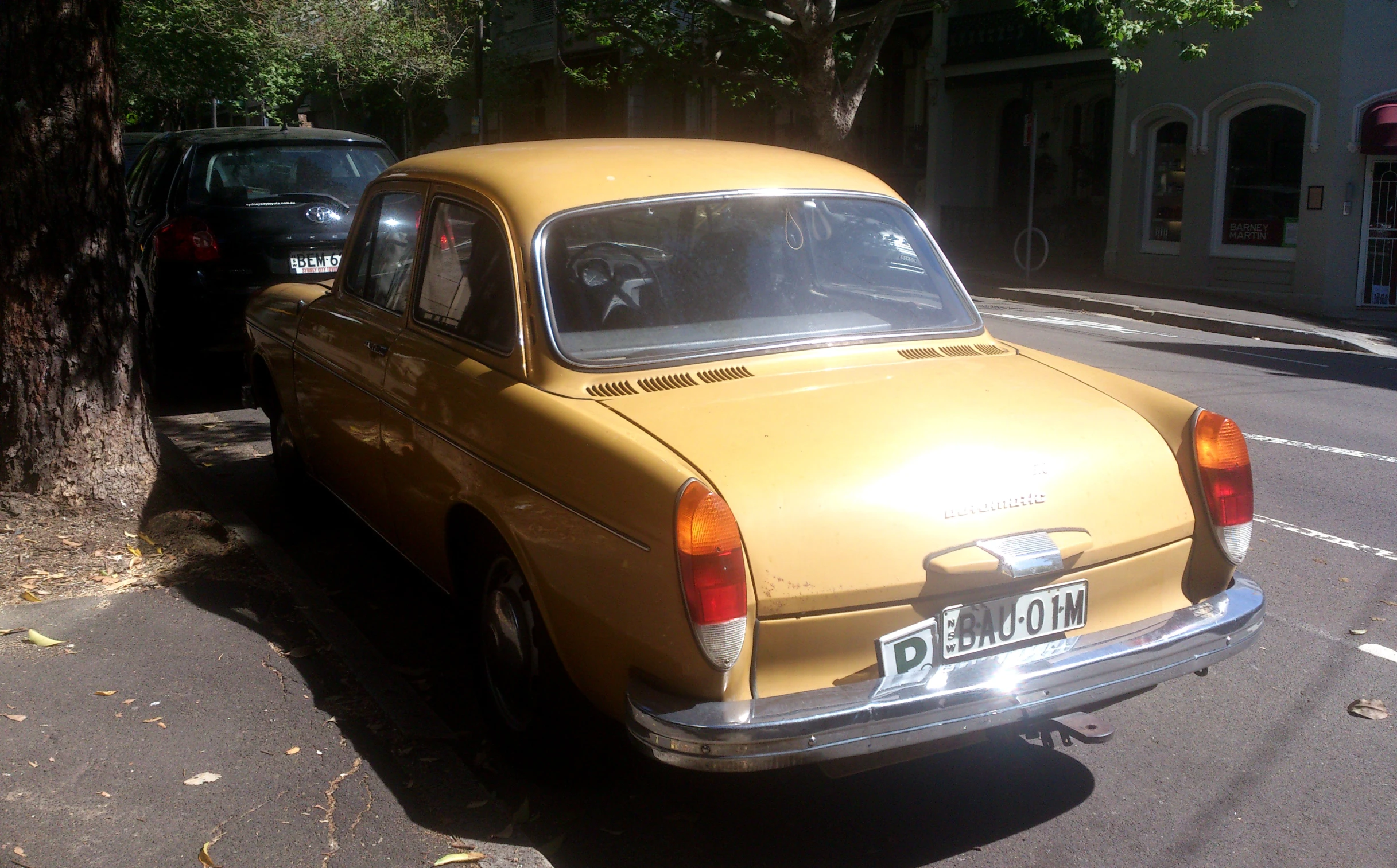 a yellow classic car is parked on the side of a road