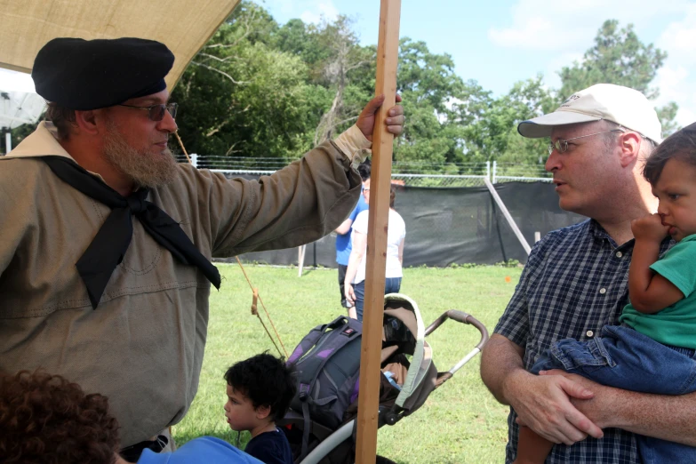 a man with a beard holding a baby under an awning