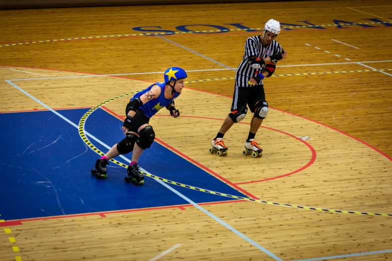 two people riding roller boards on a basketball court