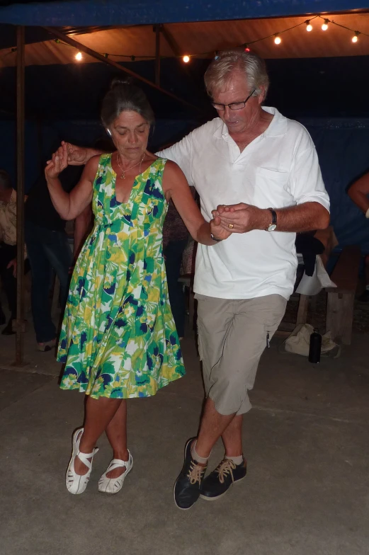 an older couple dancing in a tent under the lights