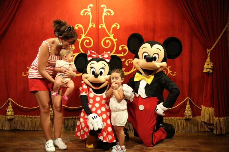 woman holding a baby and mickey mouse posing with two young children