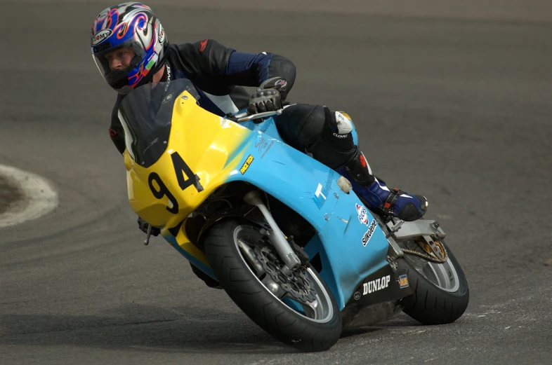 a man riding on the back of a blue and yellow motorcycle