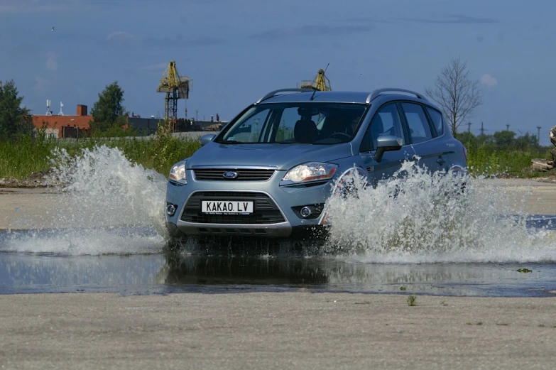 a gray minivan driving through some water