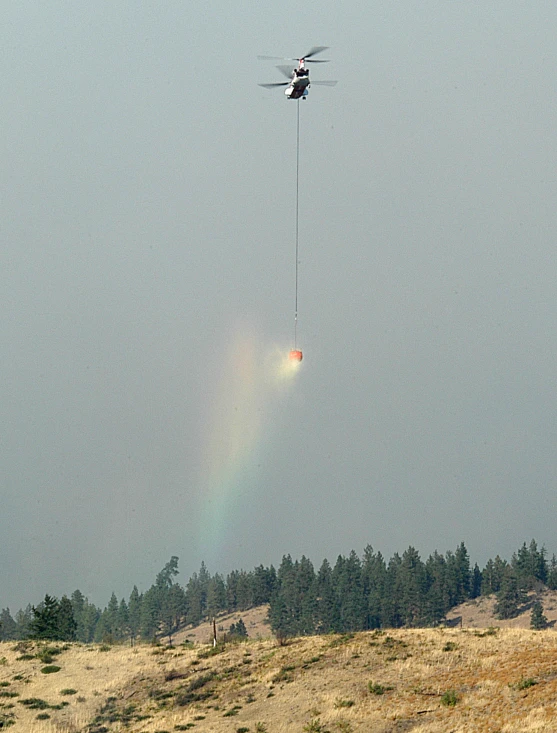 a helicopter dropping fire off the side of a hill