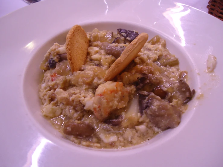 a white bowl filled with food on top of a white table