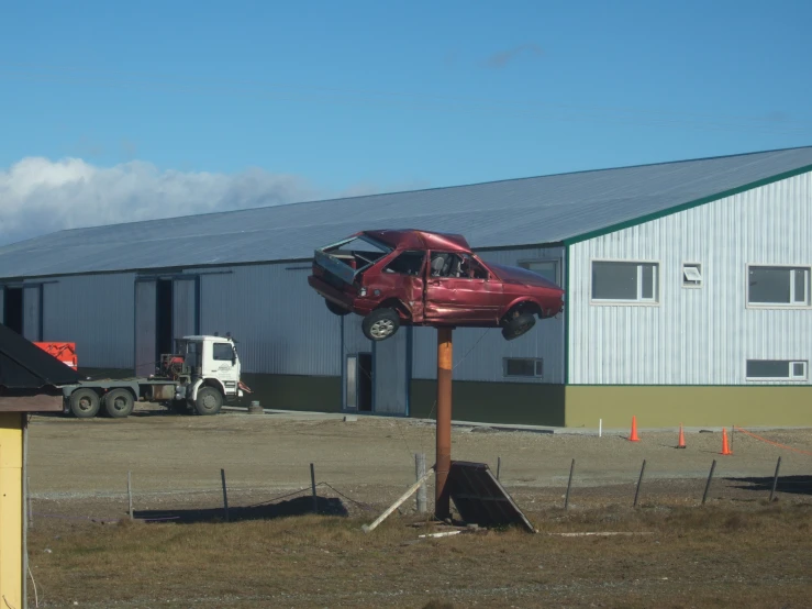 a red car is up in the air above a pole